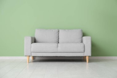 Oturma odasının içinde, yeşil duvarın yanında kanepe var.