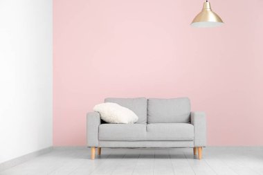 Oturma odasının içinde, pembe duvarın yanında kanepe var.