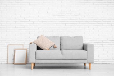 Beyaz tuğla duvarın yanında kanepesi olan oturma odasının içinde.