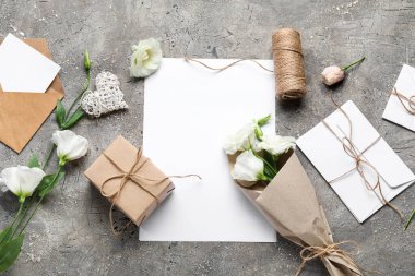 Boş kartlı kompozisyon, zarflar ve gri arkaplanda güzel östoma çiçekleri.