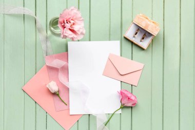 İçinde boş kartlar, alyanslar, zarf ve ahşap arkaplanda güzel çiçekler olan kompozisyon