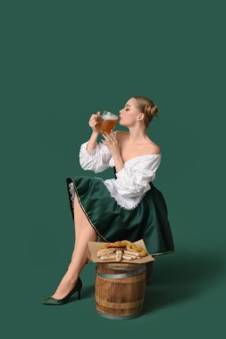 Güzel Ekim Festivali garsonu bira ve atıştırmalıklarla yeşil arka planda oturuyor.