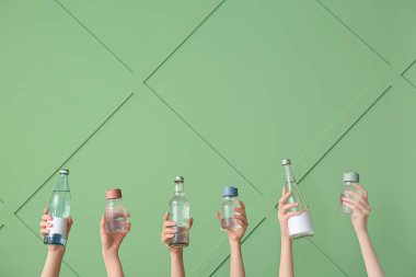 Yeşil arka planda temiz suyu olan şişeleri tutan kadınlar