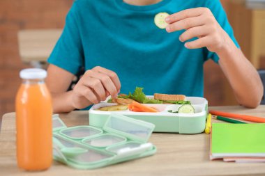 Küçük çocuk öğle yemeğini sınıfta yiyor, yakın plan.