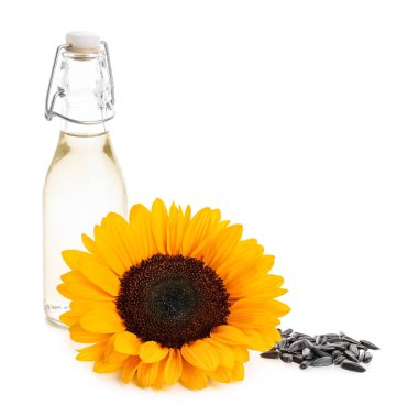Beyaz arka planda bir şişe yağ, ayçiçeği ve tohumlar.