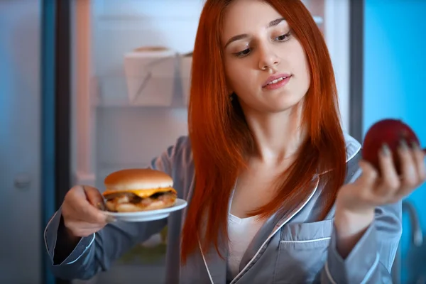 Mladá Žena Hamburgerem Jablkem Blízkosti Otevřené Lednice Kuchyni Noci Detailní — Stock fotografie