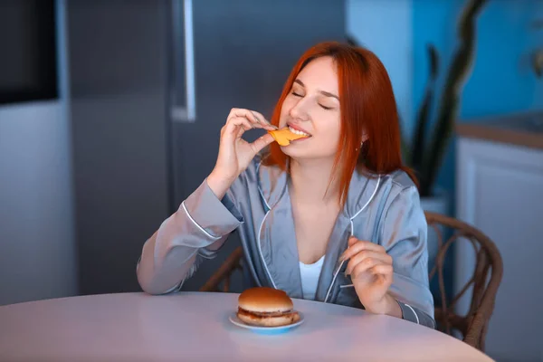 Geceleri Mutfakta Hamburger Yiyen Genç Bir Kadın — Stok fotoğraf