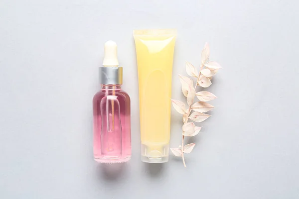 Cosmetic products and dried plant on light background