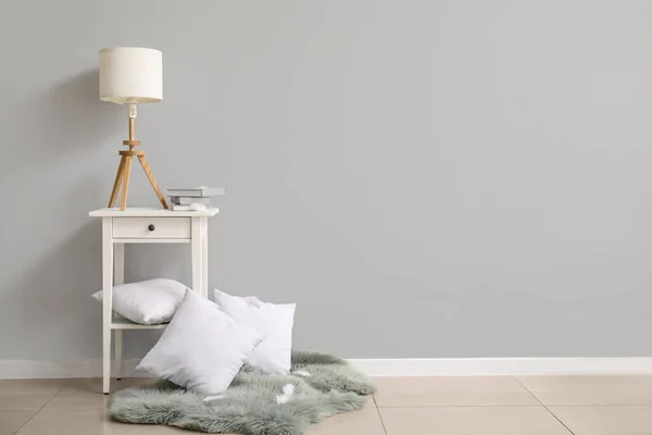 Прикроватный Столик Лампой Подушками Возле Белой Стены — стоковое фото
