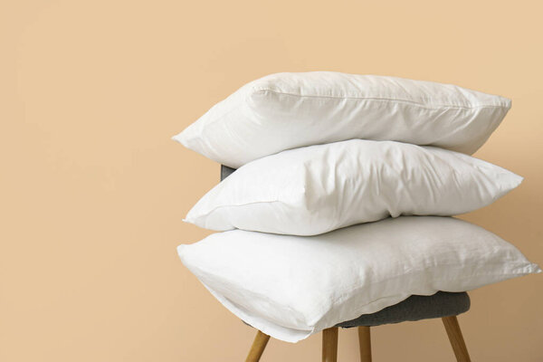 White pillows on chair near beige wall