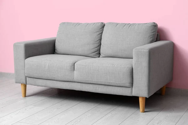 ピンクの壁の近くの居心地の良い灰色のソファ — ストック写真