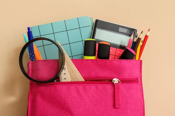 粉色学校背包 装有不同的文具和橙色背景的放大镜 — 图库照片