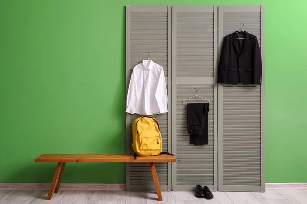 バックパック スタイリッシュな学校の制服が部屋の屏風にかかっているベンチ — ストック写真