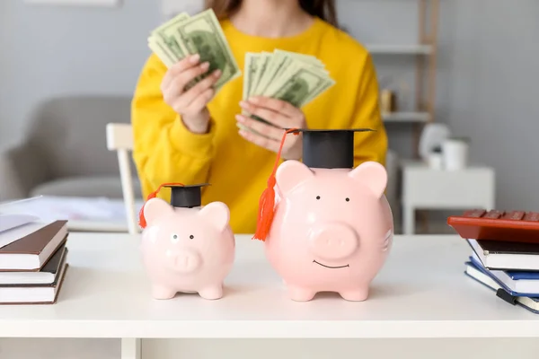 Studentinnen Die Tisch Mit Sparschweinen Abschlussmützen Geld Zählen Konzept Für — Stockfoto