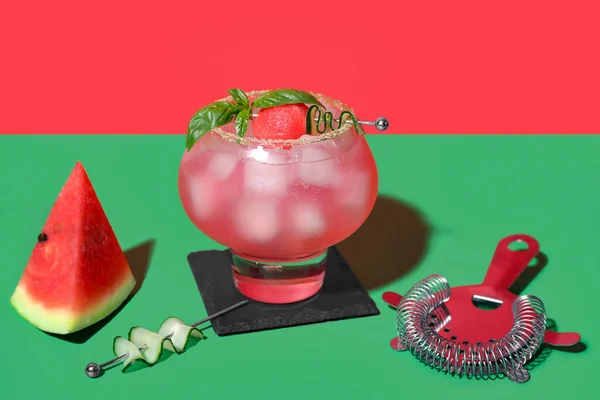 赤い壁の近くの緑のテーブルの上にストレーナーとおいしいスイカカクテルのガラス — ストック写真