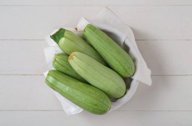 Beyaz ahşap arka planda yeşil kabaklı bir kase.