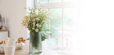 Mutfaktaki masada taze papatya çayı olan vazo. Tasarım için pankart