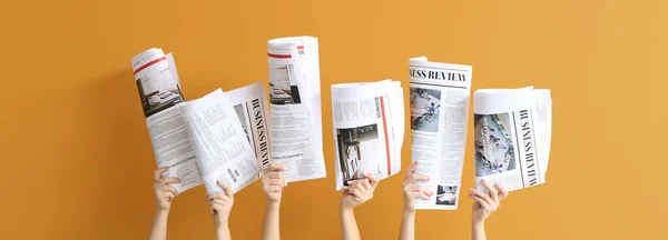 オレンジの背景に新聞を持つ女性の手 — ストック写真