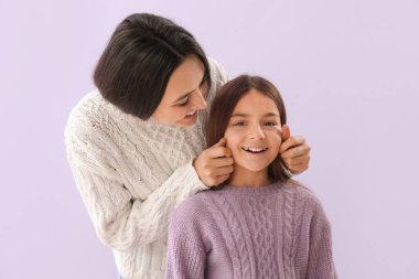 Küçük kız ve annesi sıcak kazaklar içinde leylak arka planda