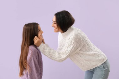 Küçük kız ve annesi sıcak kazaklar içinde leylak arka planda