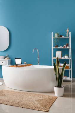 Küvetli banyo, modern dizüstü bilgisayar ve raf ünitesi.