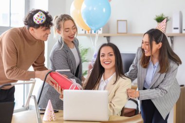 Bir grup iş adamı iş arkadaşlarını doğum günü partisinde hediyeyle selamlıyor.