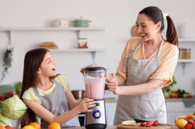 Küçük kız ve annesi mutfakta blender ile smoothie yapıyorlar.