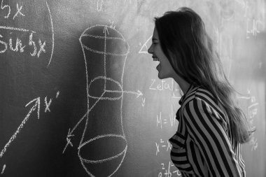 Sınıfta tahtaya yakın kızgın kadın matematik öğretmeni.