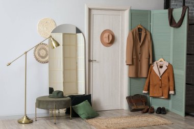 Koridorun içinde askı, ayna, kapı ve paltolar var.