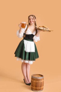 Beautiful Octoberfest waitress with beer and snacks on beige background clipart