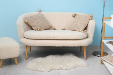 Mavi duvarın yanında rahat beyaz kanepe ve kanepe