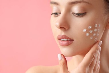 Pembe arka planda krem sürmüş güzel bir genç kadın.