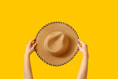 Sarı arka planda hasır şapkalı kadın elleri