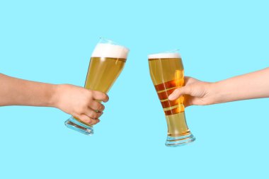 Soğuk bira bardaklı kadın elleri mavi arka planda şıngırdıyor