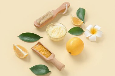 Bir kase limonlu vücut fırçası ve açık sarı arka planda deniz tuzu.
