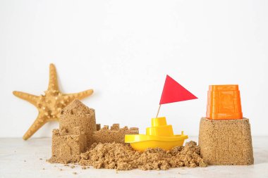 Plaj oyuncaklarıyla kumdan kale ve beyaz arka planda bayrak