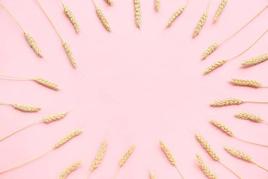 Pembe arka planda buğday kulaklarından yapılmış çerçeve