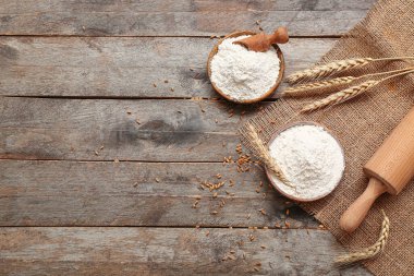 Tahta masa üzerinde buğday unu ve oklavalı kase.