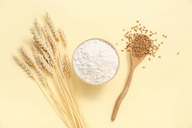 Sarı arka planda buğday unu, kaşık ve dikenli kase.