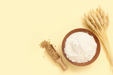 Sarı arka planda buğday unu, kepçe ve çivili kase.