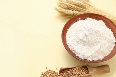 Sarı arka planda buğday unu, kepçe ve çivili kase.
