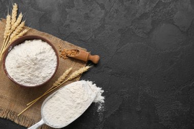 Siyah grunge arkaplanda buğday unu ve dikenli kase.