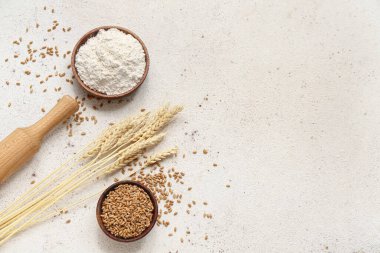 Üzerinde buğday unu, tahıl, merdane ve gri arka planda çivi olan kaseler.