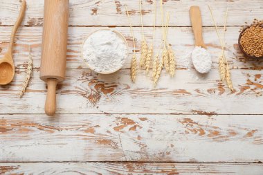 Beyaz ahşap masa üzerinde buğday unu, merdane iğnesi ve çivilerle kompozisyon