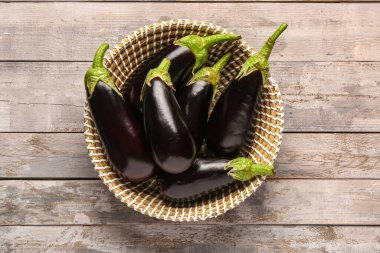 Gri ahşap arka planda taze patlıcan dolu hasır kase.