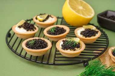 Yeşil arka planda siyah havyarlı lezzetli tartların ızgarası.