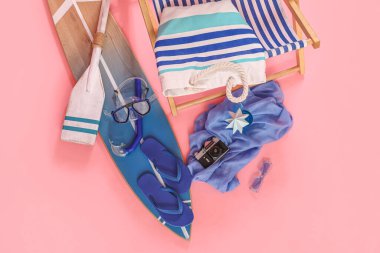 Pembe arka planda plaj aksesuarları ve fotoğraf makinesi.