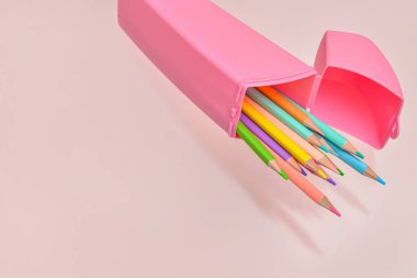 Pembe arka planda renkli kalemli bir kutu