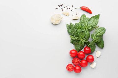 Taze fesleğen, kiraz domatesleri ve gri arka planda biber.