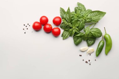 Taze fesleğen, kiraz domatesleri ve gri arka planda biber.